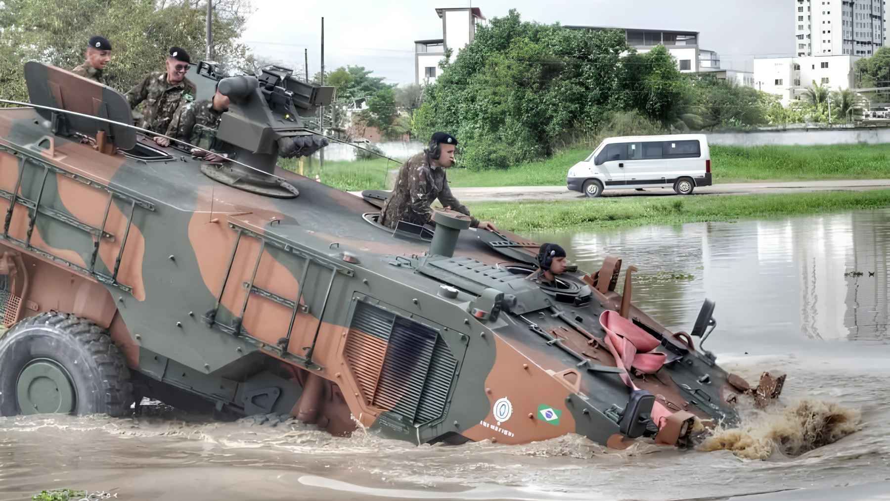 Brazilian Guarani armored vehicle crossing water with soldiers during an amphibious operation.