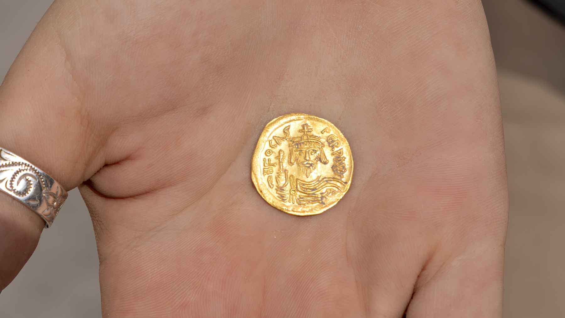 A metal detector uncovers a 1,400-year-old Byzantine treasure, and the coins reappear as if they were hidden yesterday 1 A Byzantine gold coin from the time of Emperor Heraclius held in a person’s hand after being uncovered in Israel.