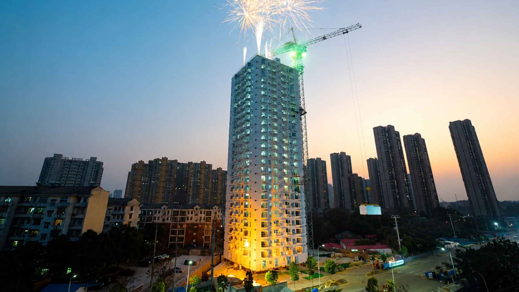 Completed modular residential tower in China lit up at night with fireworks celebrating rapid construction.