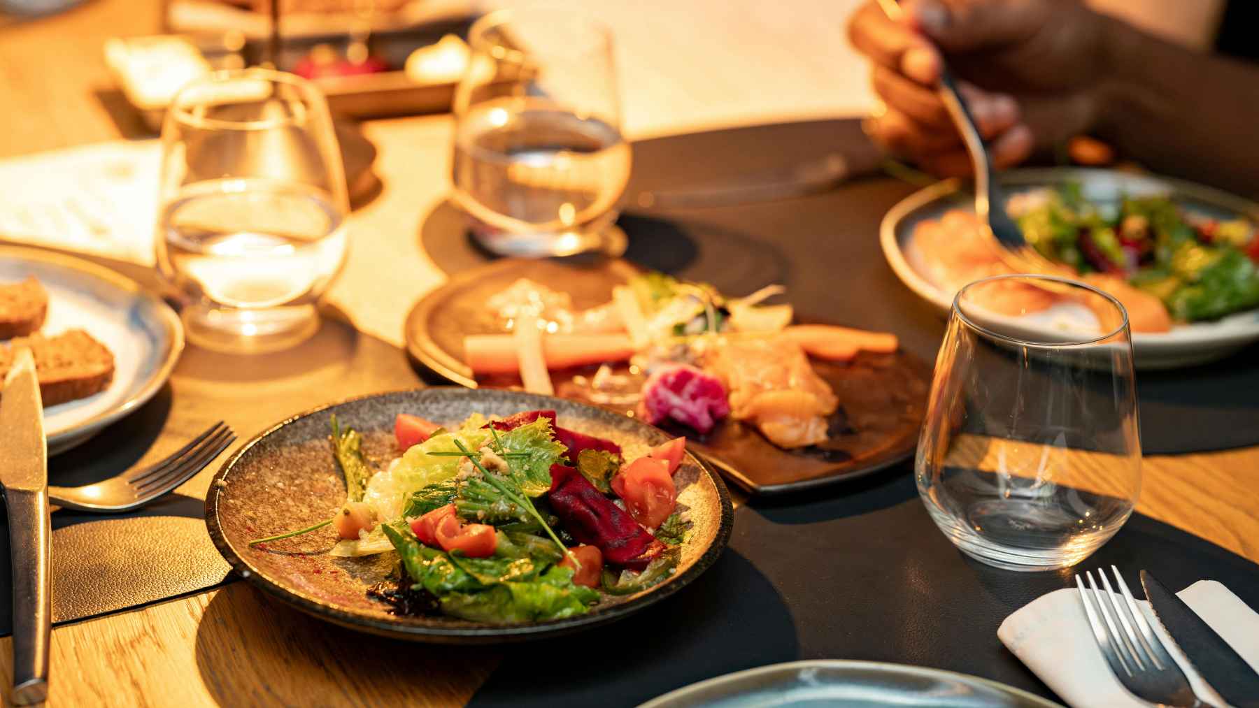 Dinner table with salads, bread, water glasses, and plates of food, reflecting research on hidden food chemicals.