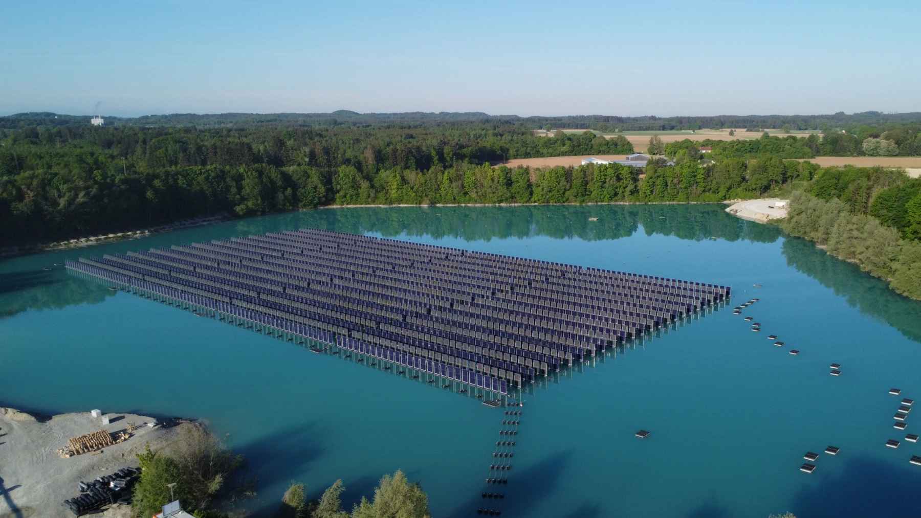 Germany covers an artificial lake with solar panels without harming the ecosystem, and the experiment hints at a future where water becomes a rooftop for power 1 Aerial view of a floating solar farm covering part of an artificial lake in Germany with rows of solar panels on water.