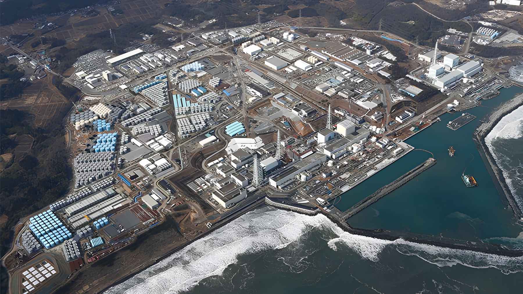 Aerial view of Fukushima Daiichi nuclear plant with rows of water storage tanks along the coast.