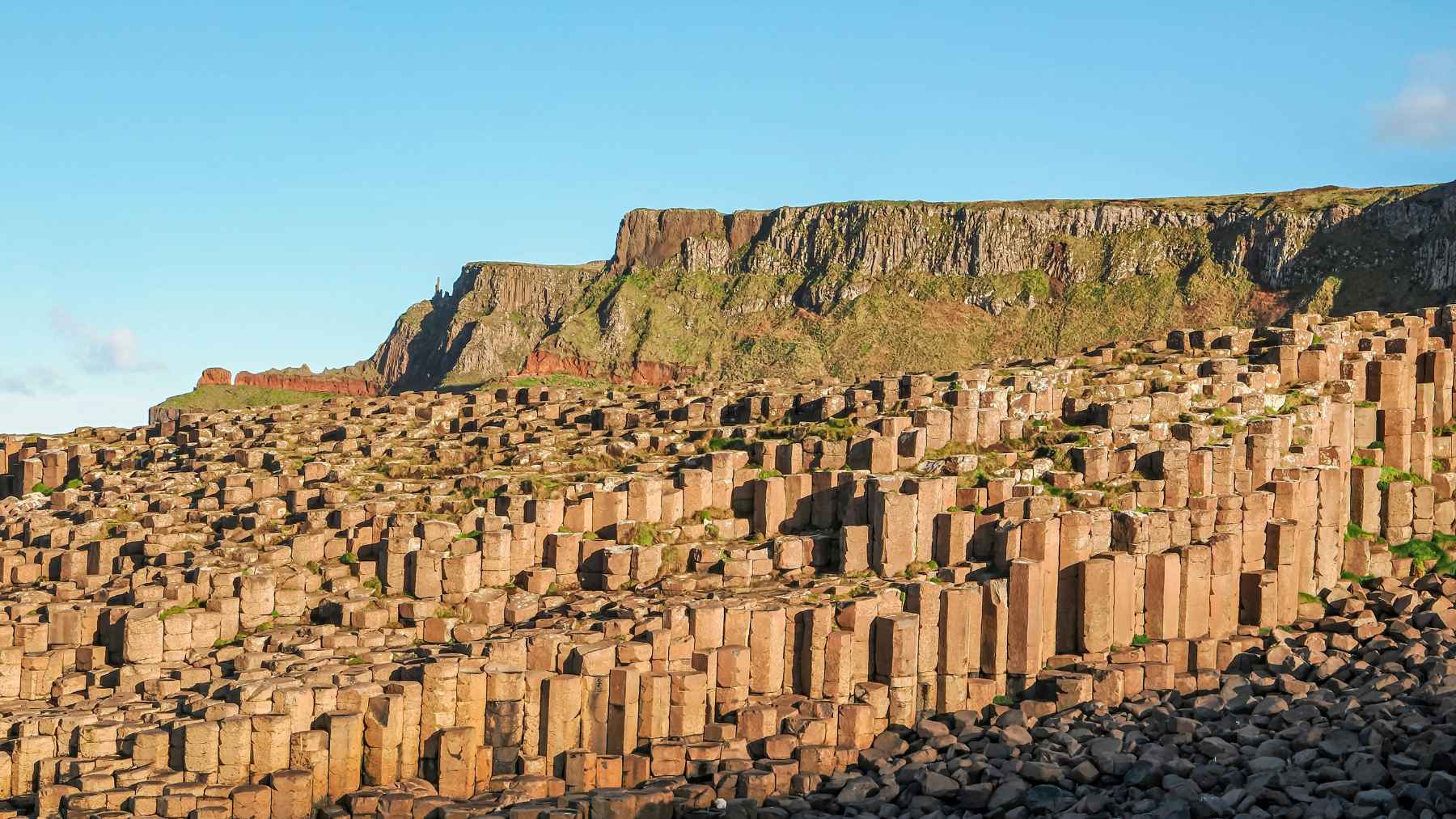 The Giants' Causeway was not formed as a result of a battle between giants, but rather by an explosive volcanic event that took place 60 million years ago—an event that, as scientists have now determined, occurred over a shorter period of time 1 Hexagonal basalt columns at Giant’s Causeway with coastal cliffs rising behind them in County Antrim, Northern Ireland.