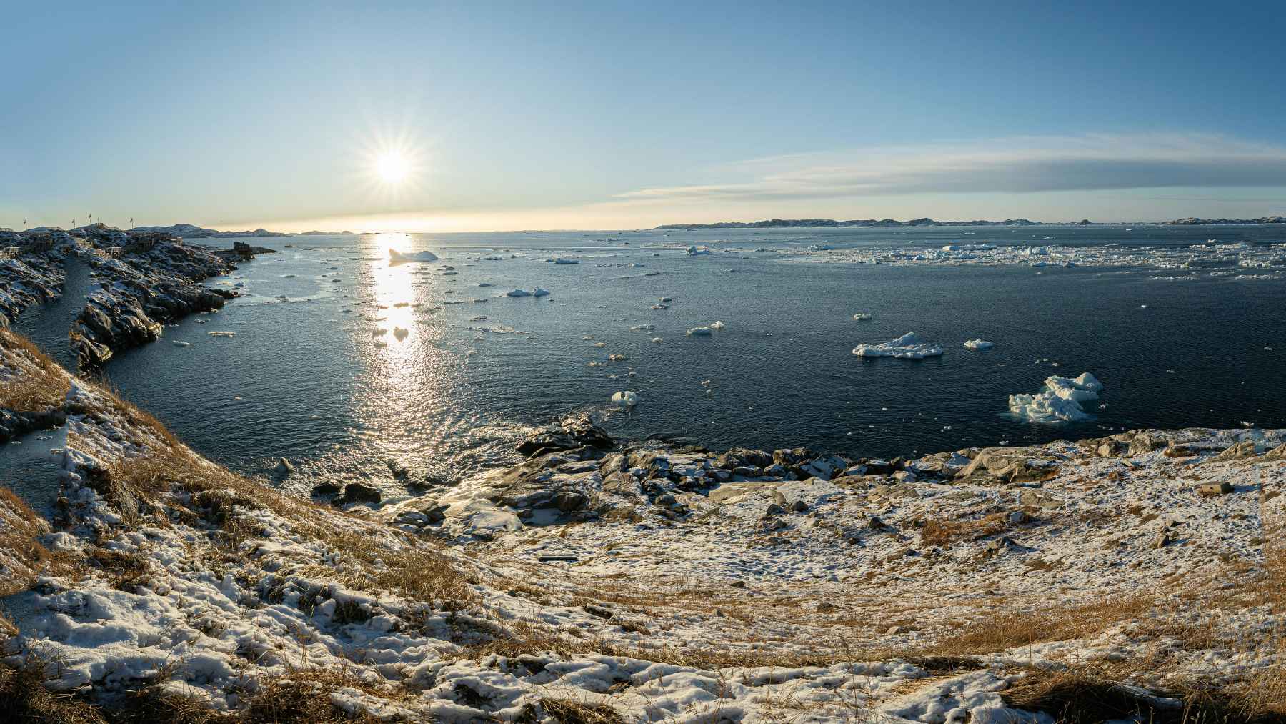 Snow-covered Greenland coastline with floating ice, representing the Arctic landscape where ancient middens were preserved in permafrost.