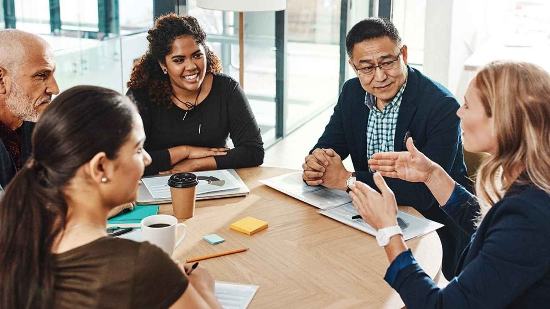 Group of people in a meeting listening and discussing ideas, illustrating how individuals reconsider opinions in conversations.