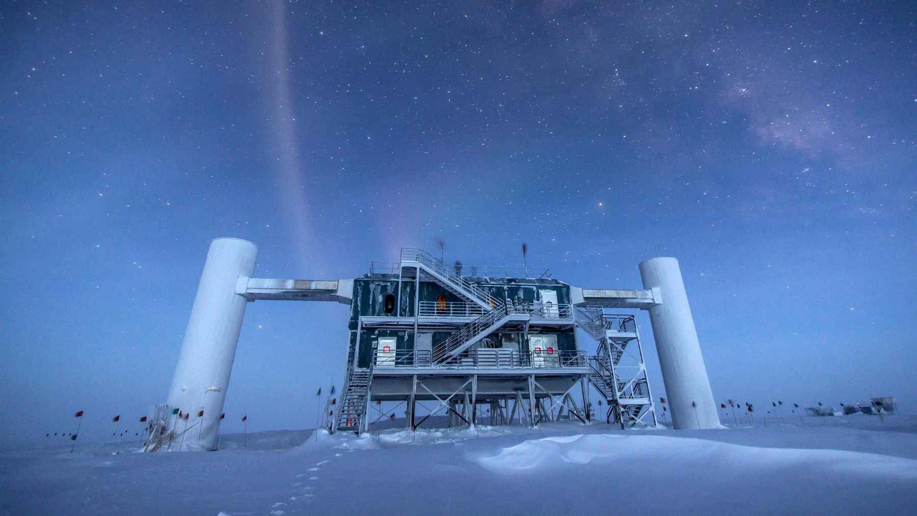IceCube neutrino observatory at the South Pole under a star filled Antarctic sky.