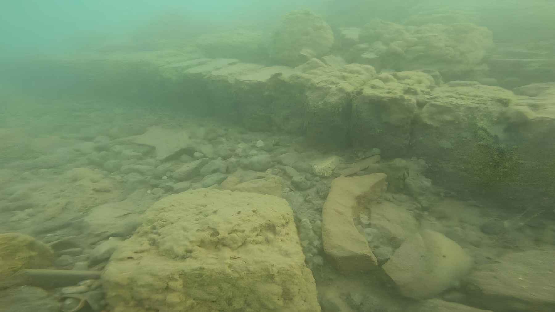 Submerged stone structures and ruins visible underwater at Lake Issyk-Kul, part of a medieval Silk Road settlement.