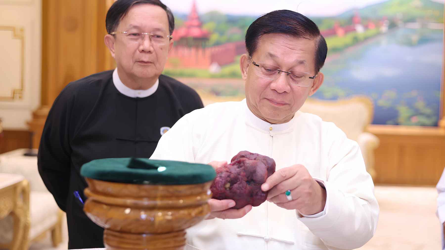 Myanmar officials examine a massive rough ruby discovered in Mogok, highlighting the scale of the 11,000-carat gemstone.