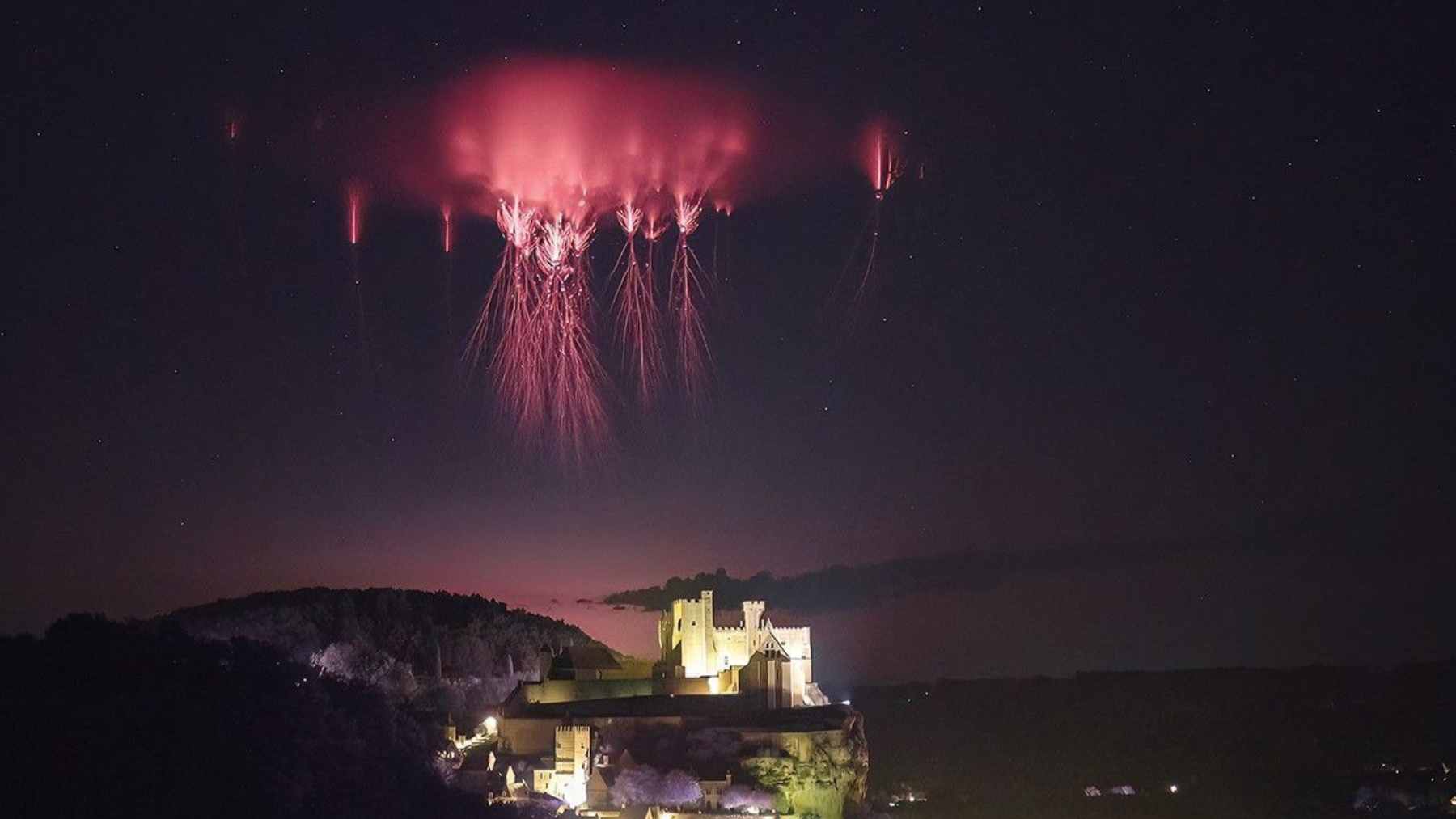 A view from the International Space Station showing a vibrant red gigantic jet lightning event discharging above a thunderstorm.