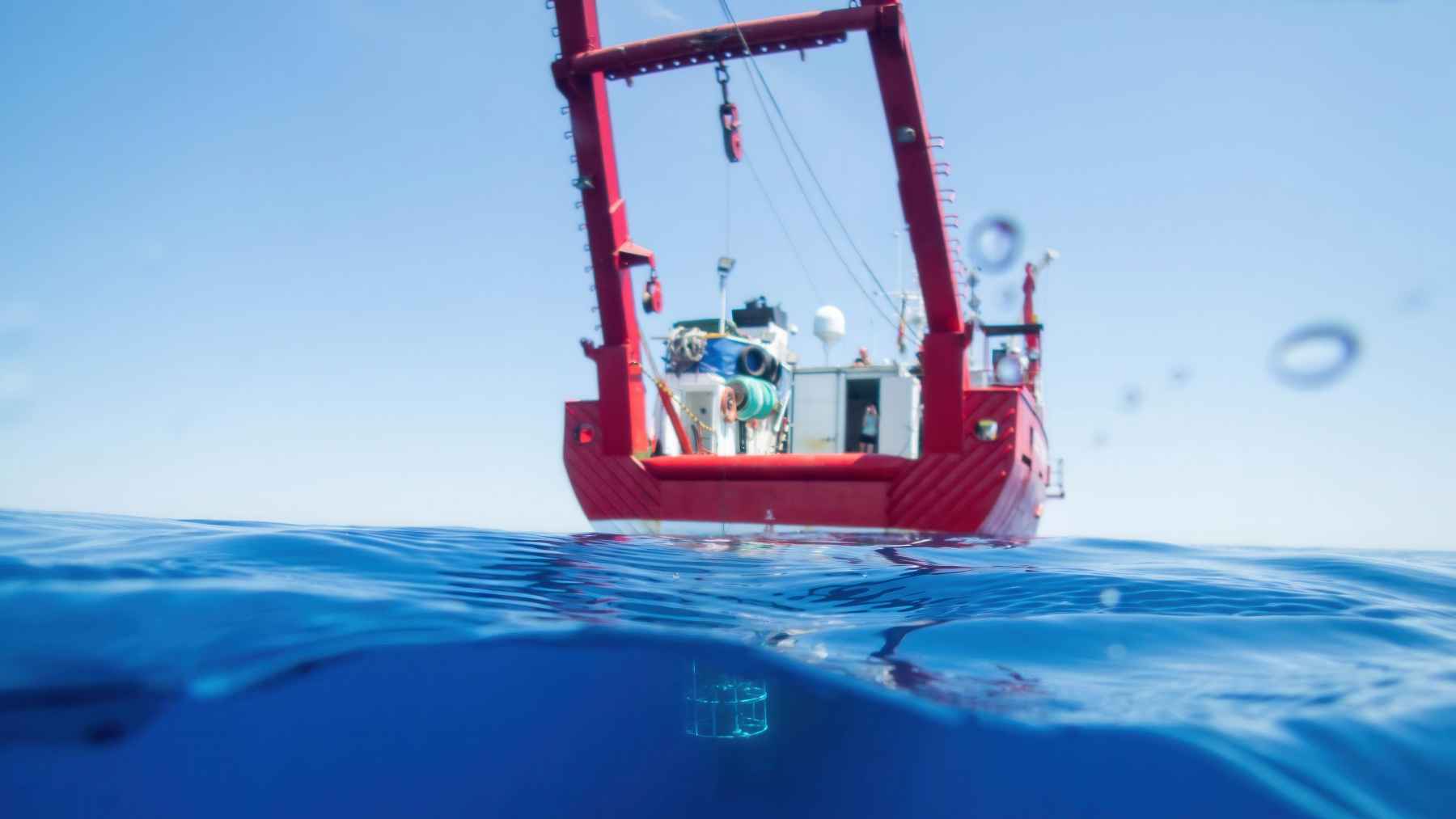 Ocean research vessel deploying a deep-sea monitoring instrument used to study ocean changes and currents.