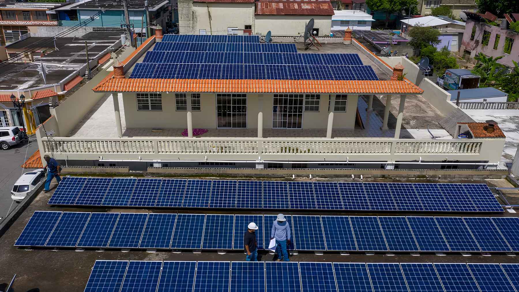 Large rooftop and ground-mounted solar panels at a residential property in Puerto Rico, with workers on site.
