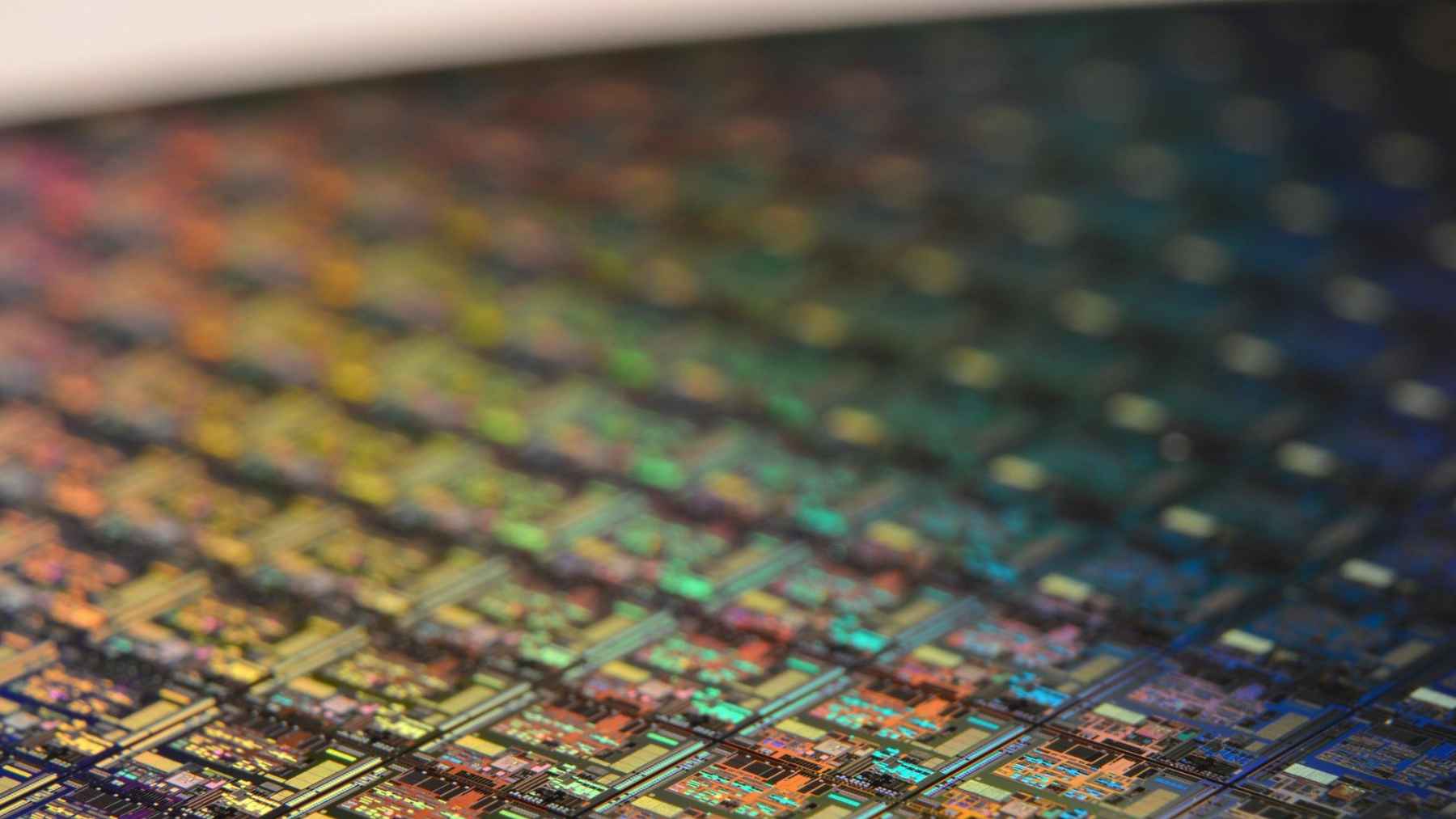 Close-up of a colorful semiconductor wafer surface used to represent atomic-layer chip research and future electronics.