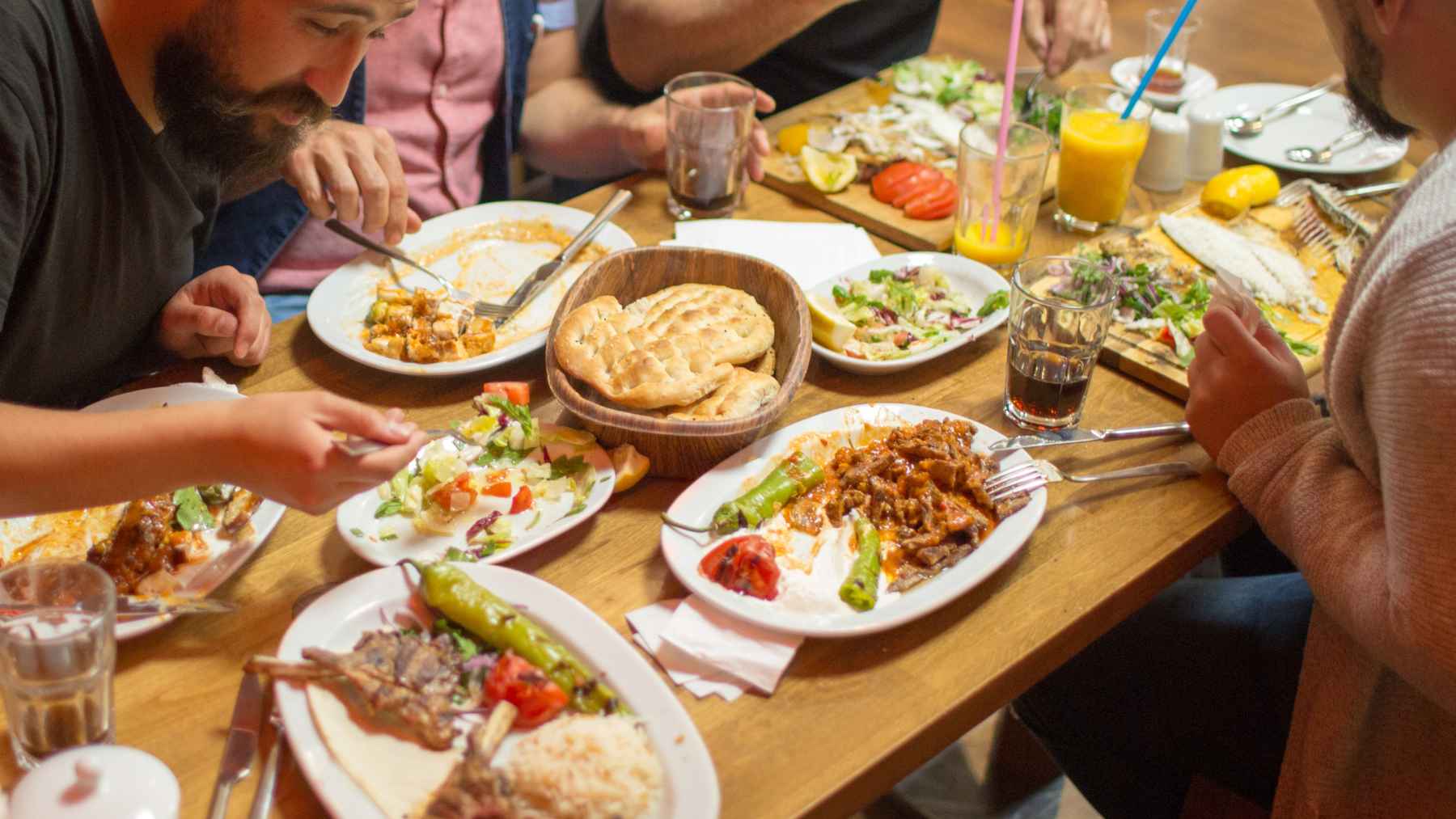 People sharing a meal with bread, vegetables, fish, meat, and drinks, illustrating the hidden chemistry in everyday food.
