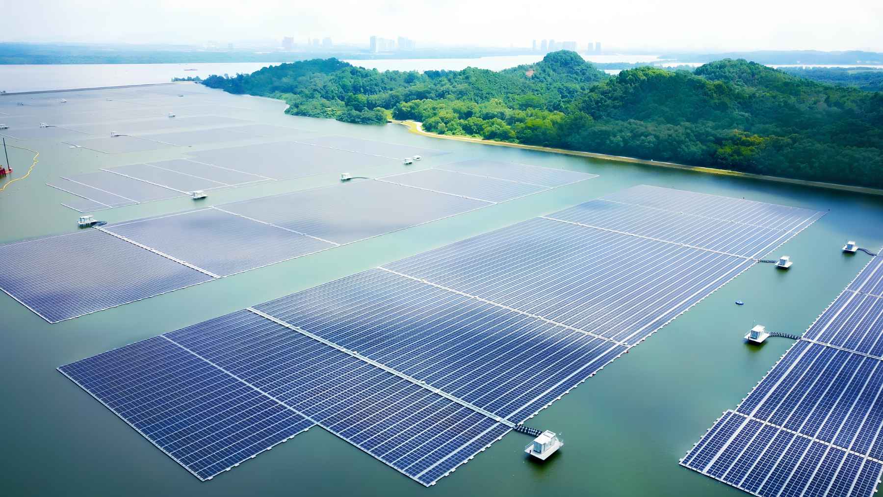 Aerial view of floating solar panels covering a reservoir in Singapore with green islands in the background.