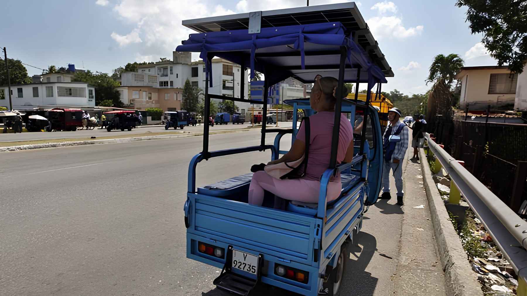 Driver using an electric tricycle with a solar panel roof in Havana, boosting range and supporting daily work.