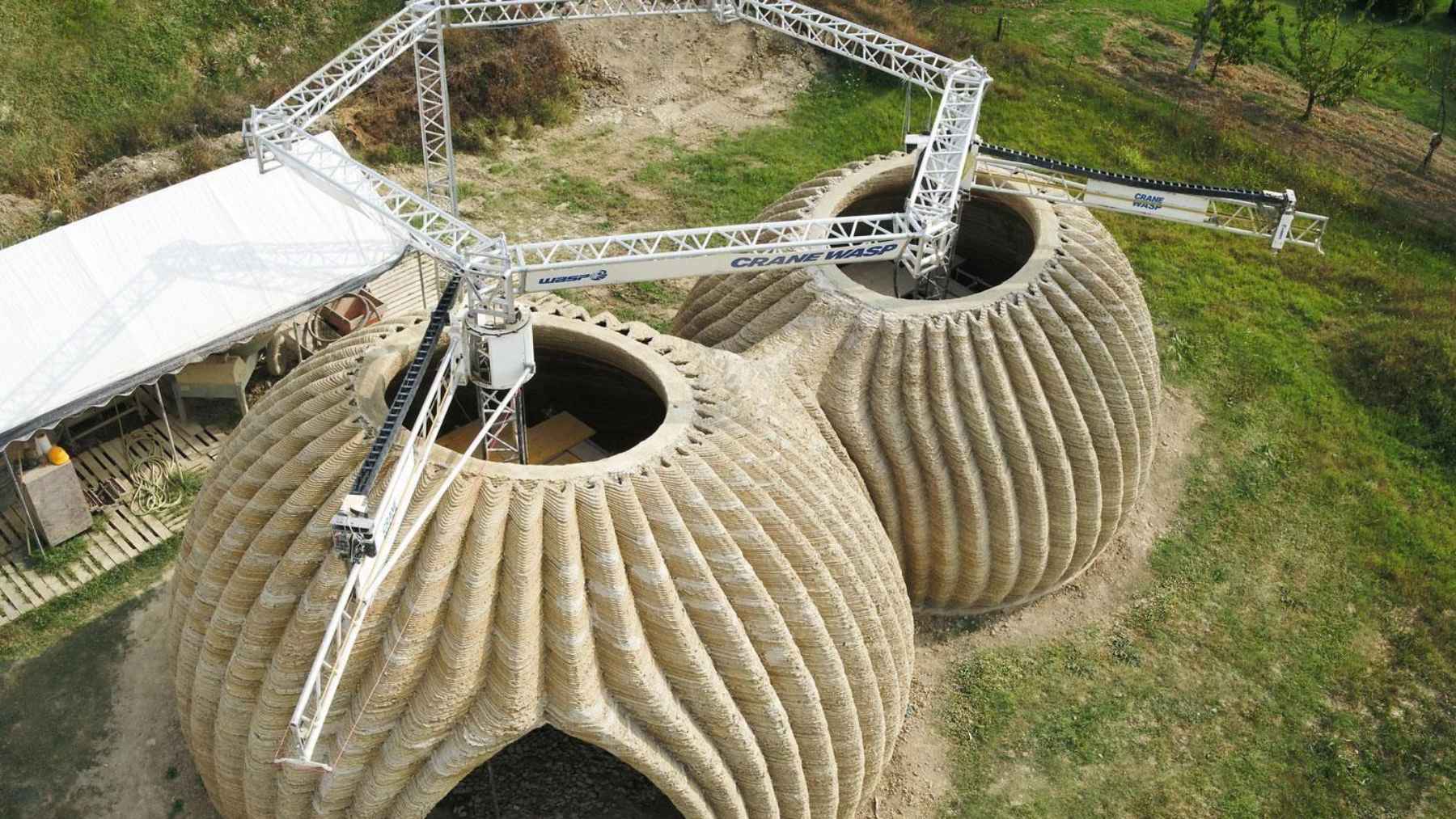 Large 3D printer building clay dome structures for the TECLA house using local soil in Italy.