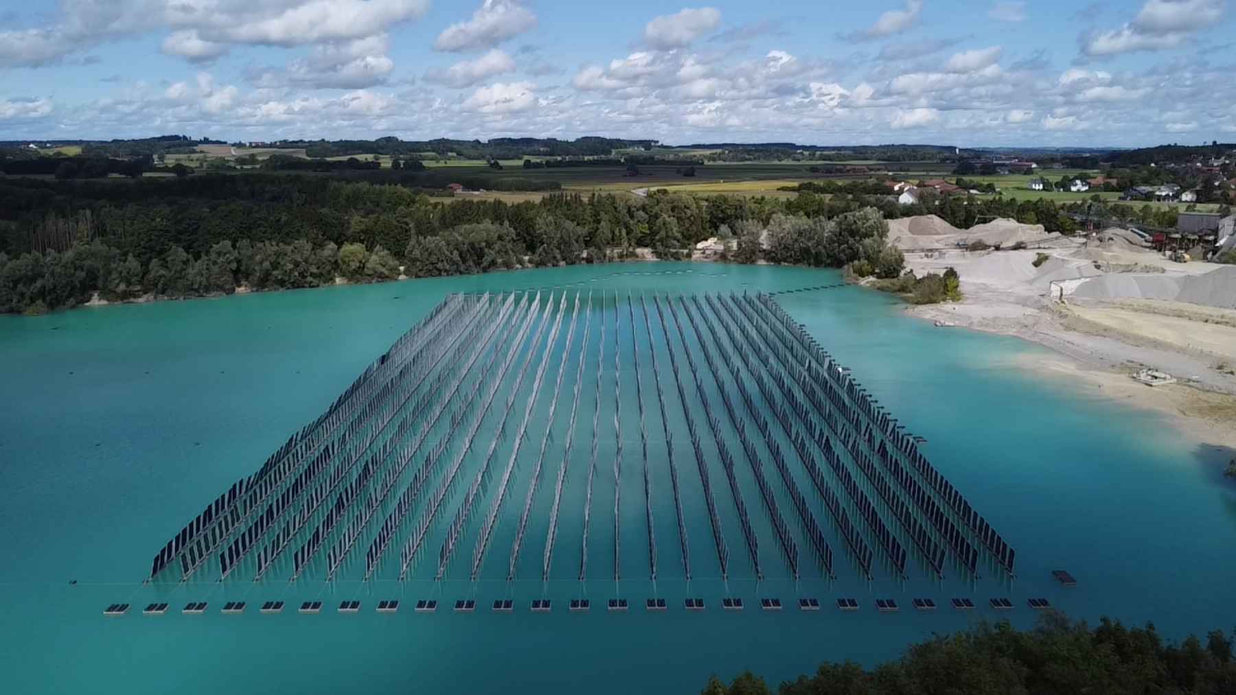 Rows of vertical floating solar panels installed on a lake, designed to capture sunlight from both sides.