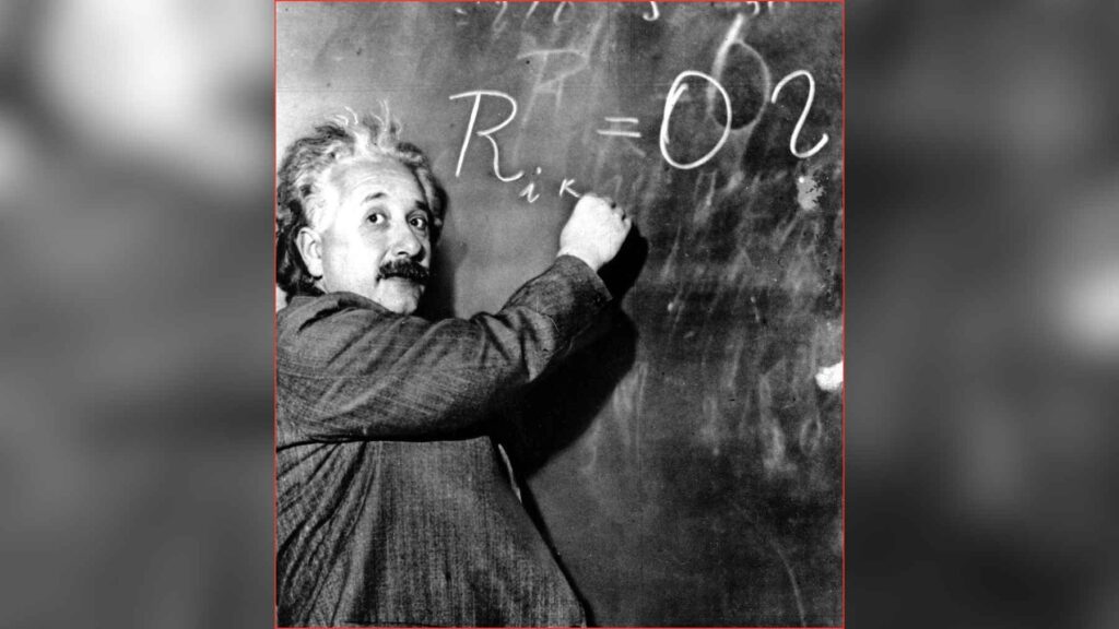 Albert Einstein writing equations on a blackboard related to fundamental laws of physics