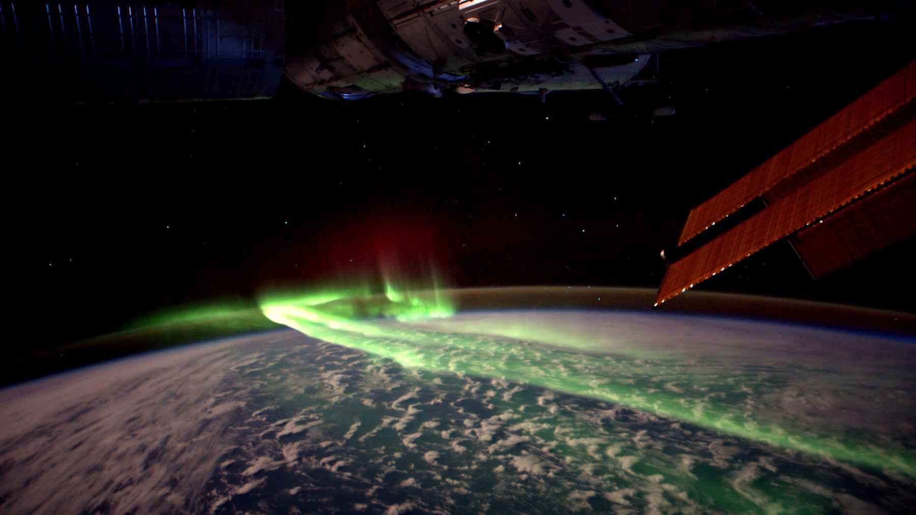 A NASA astronaut filmed the southern lights swirling like neon paint, turning orbital night into a free light show 1 Southern lights arc over Earth with International Space Station solar panels visible against the darkness of space.