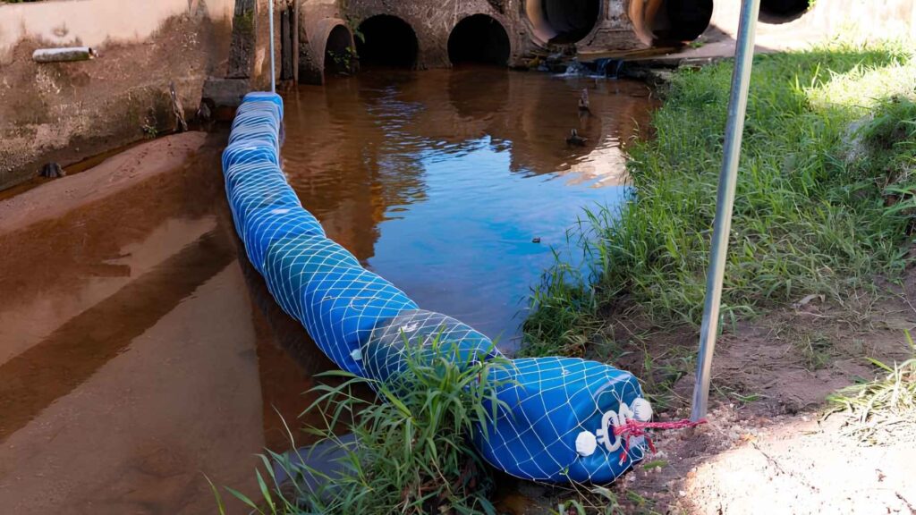 Floating barrier installed across urban river to intercept plastic and debris
