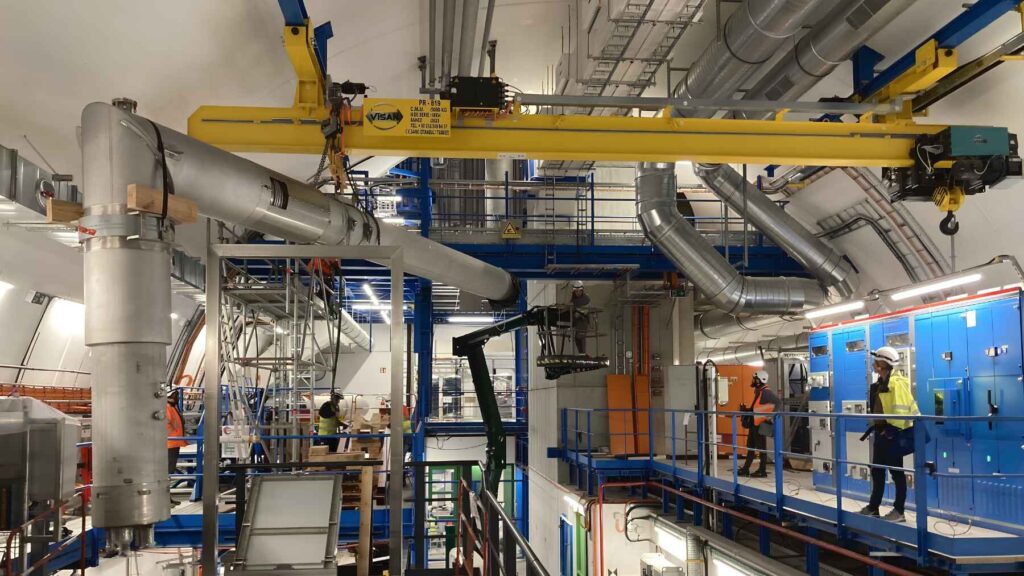 Engineers work in an underground service hall installing new magnets, cryogenic lines, and power systems for the High-Luminosity LHC upgrade.