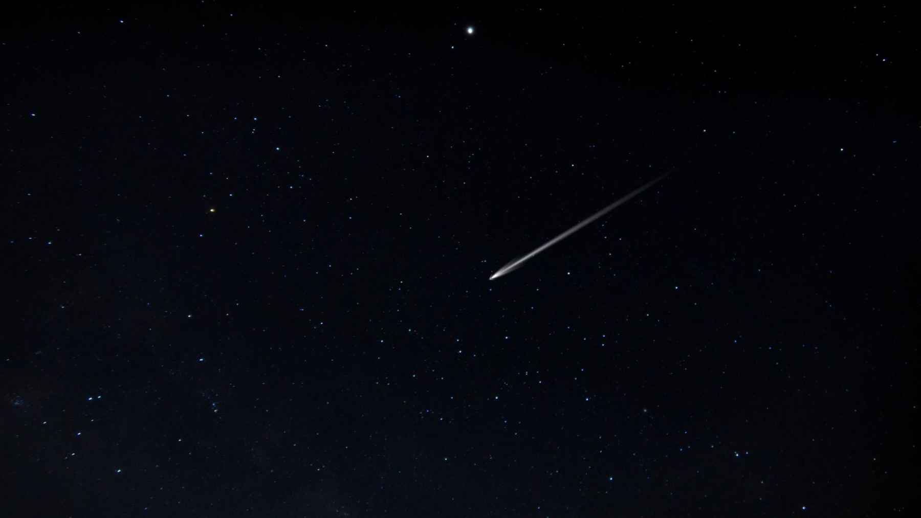 Single meteor streak crossing a dark night sky during the June Bootids meteor shower.