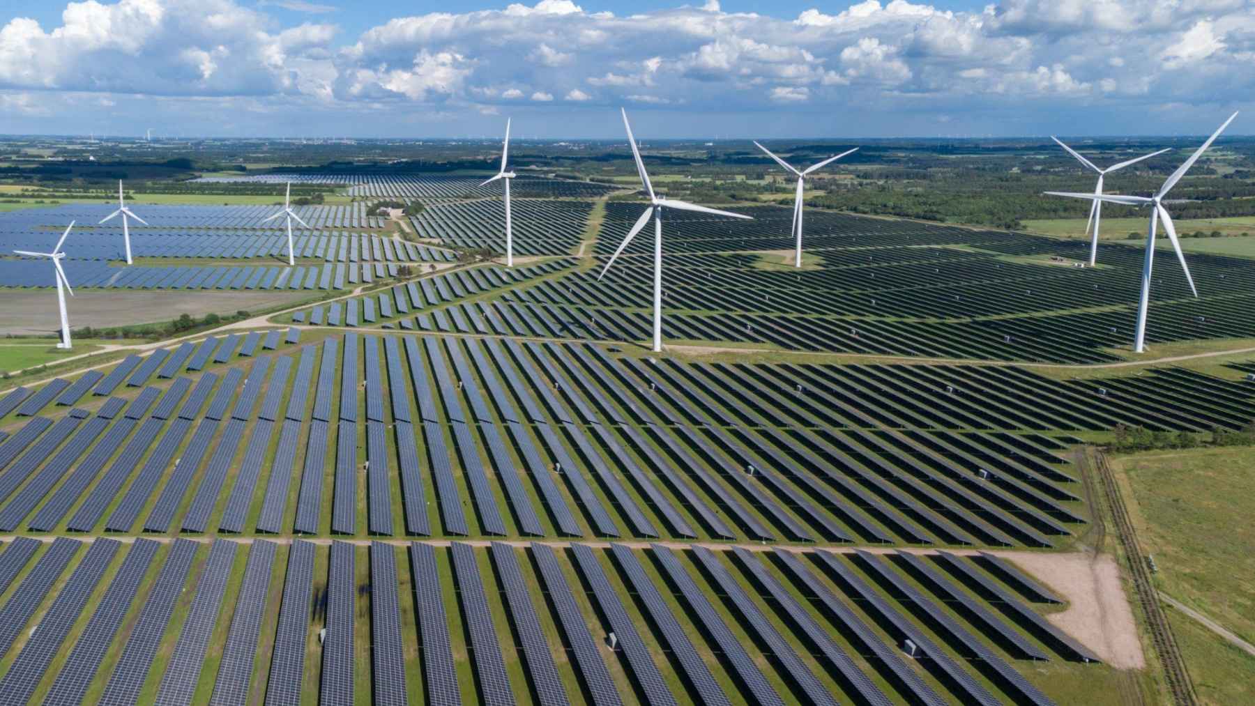 Extensive solar panel fields and wind turbines showing large-scale renewable energy infrastructure.