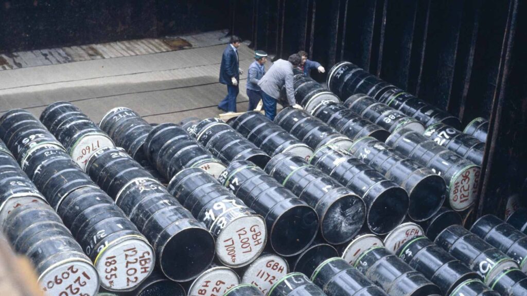 Deep-sea images show corroded radioactive waste barrels on the Atlantic Ocean floor, colonized by various marine organisms including anemones and sponges.