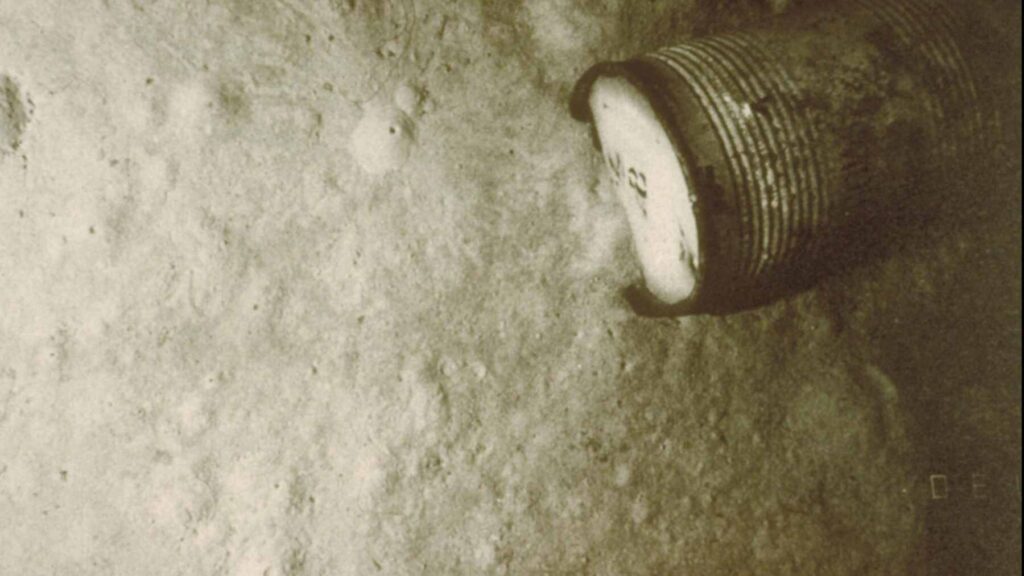 A deep-sea submersible camera captures a corroded radioactive waste barrel on the seafloor, now colonized by sponges and anemones.
