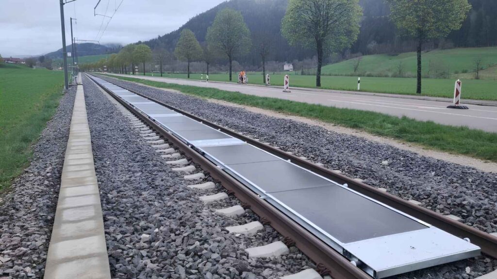 Solar panels installed between railway tracks in a rural area without disrupting train lines