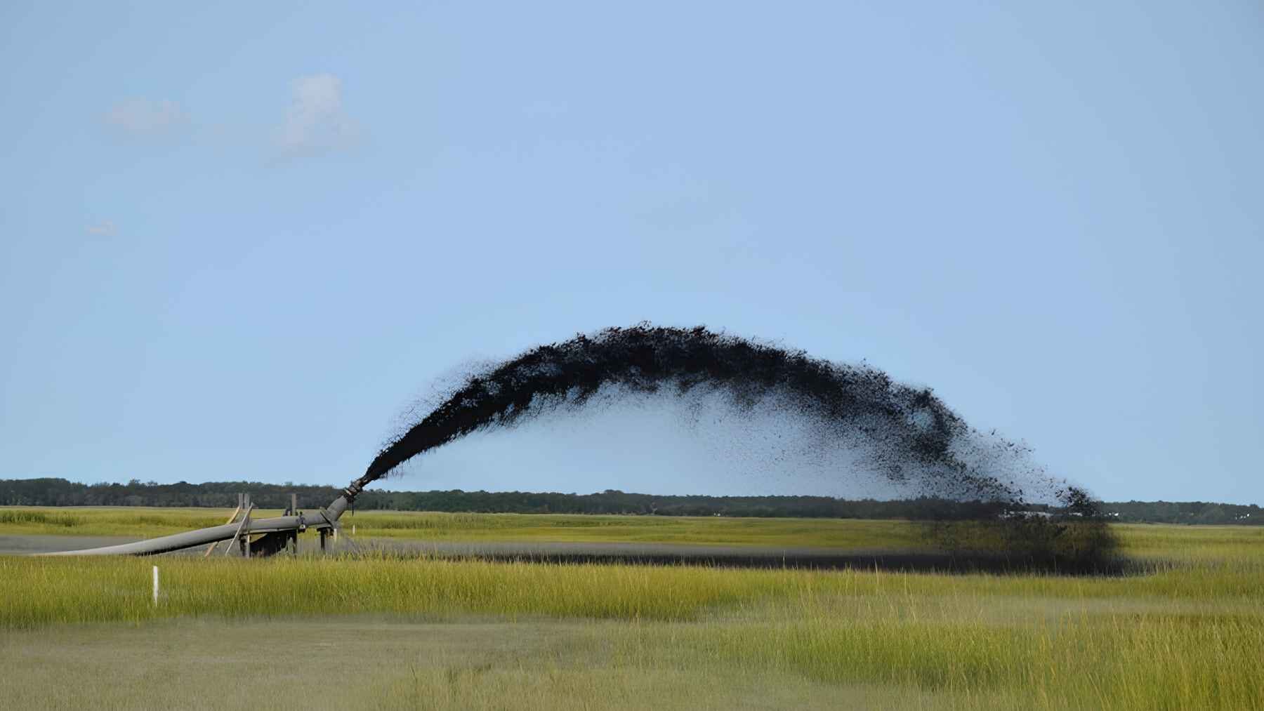 Sediment is sprayed onto a coastal marsh during a wetland restoration project to help build elevation.