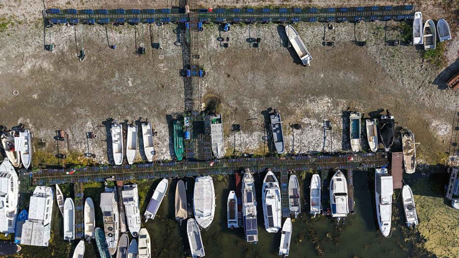 Aerial view of boats and docks surrounded by exposed riverbed during extremely low water levels on the Danube.