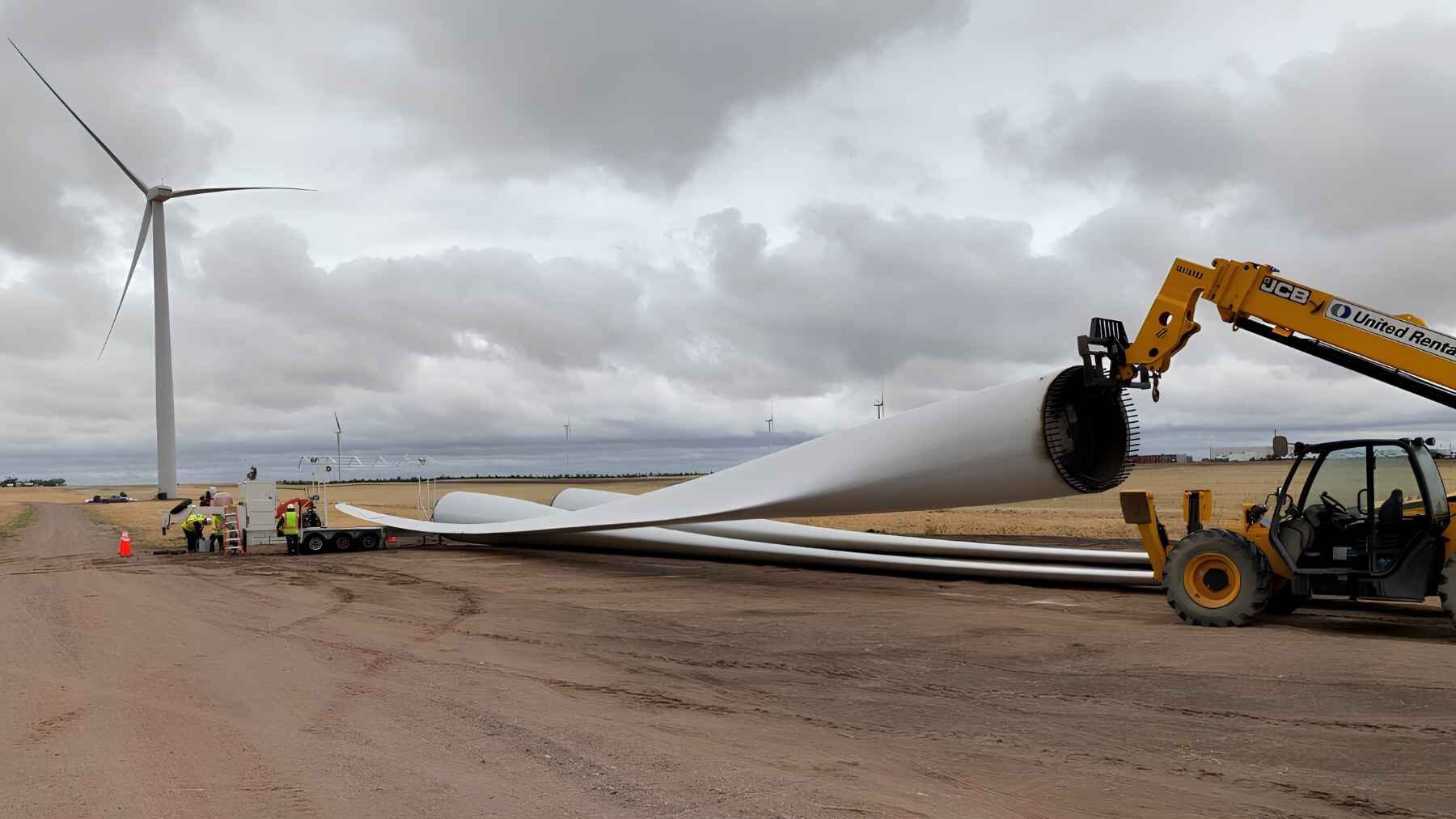 Heavy equipment moving a retired wind turbine blade at a wind farm.