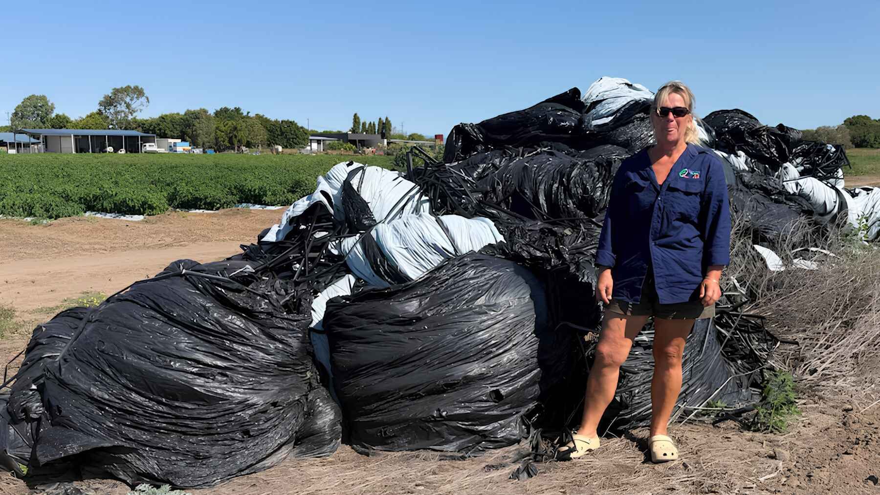Jodi Brown stands beside a large stockpile of used agricultural plastic on her family farm in Bowen, Queensland.