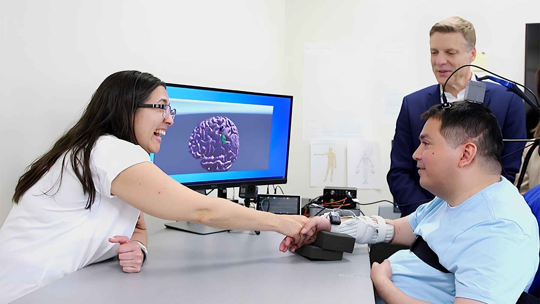 Keith Thomas moves his hand during neural bypass therapy as researchers monitor his brain activity.