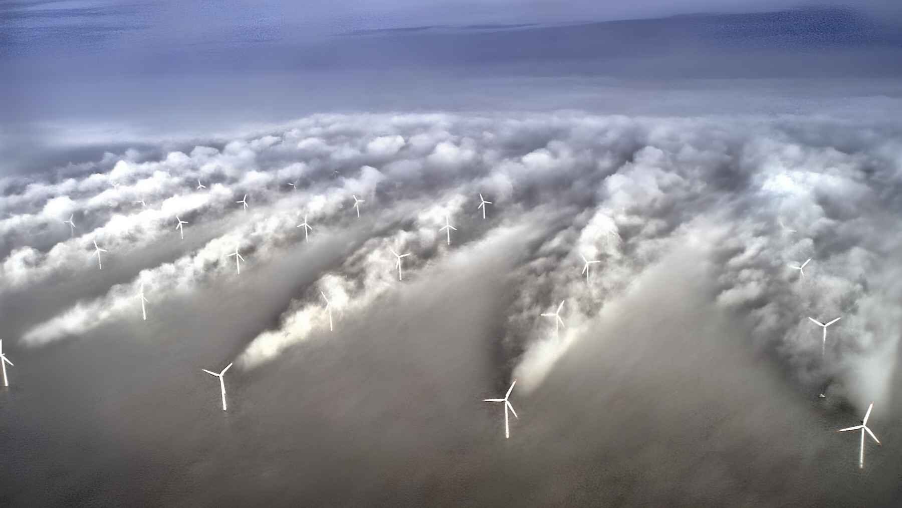 Offshore wind turbines producing visible turbulent wakes through fog at the Horns Rev wind farm.