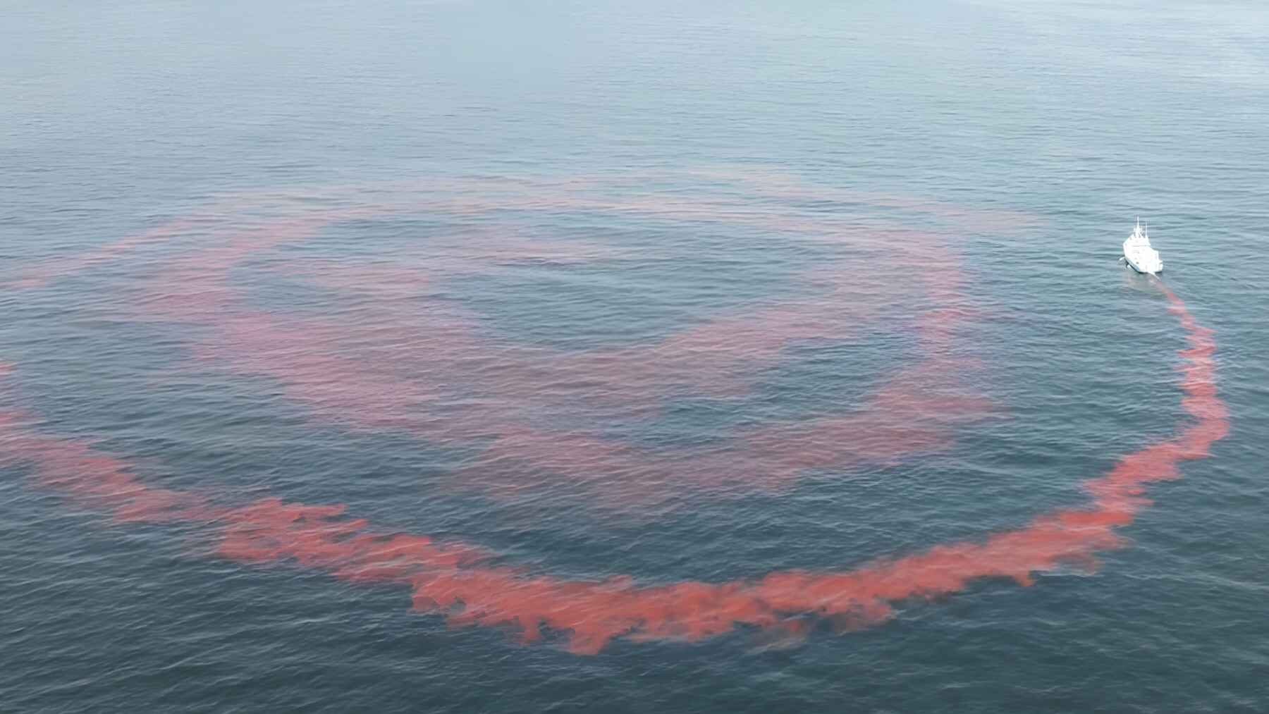 A research vessel traces a large pink dye pattern during an ocean alkalinity field experiment.