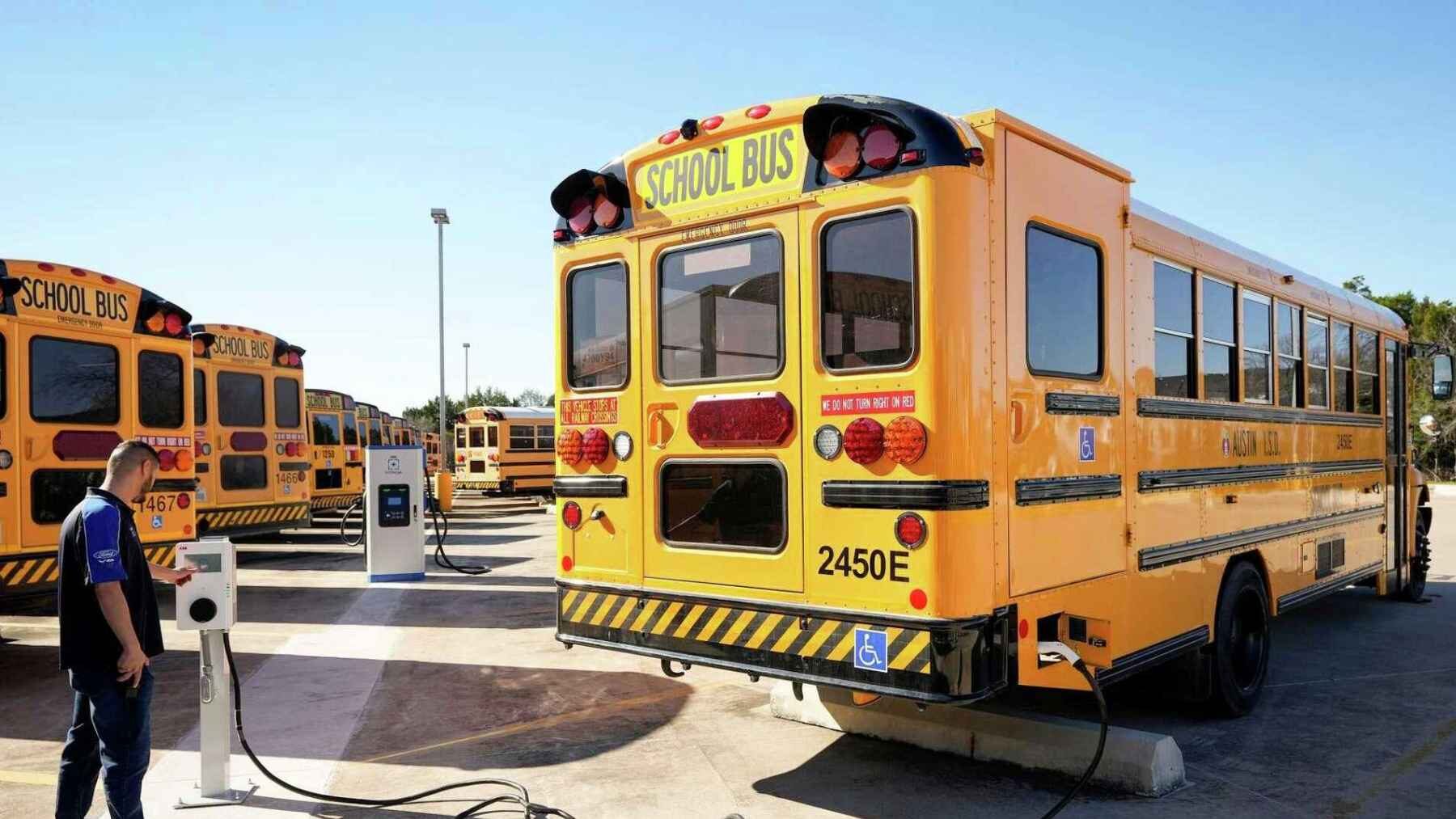 Electric school bus connected to a charging station at an Austin ISD bus depot in Texas.