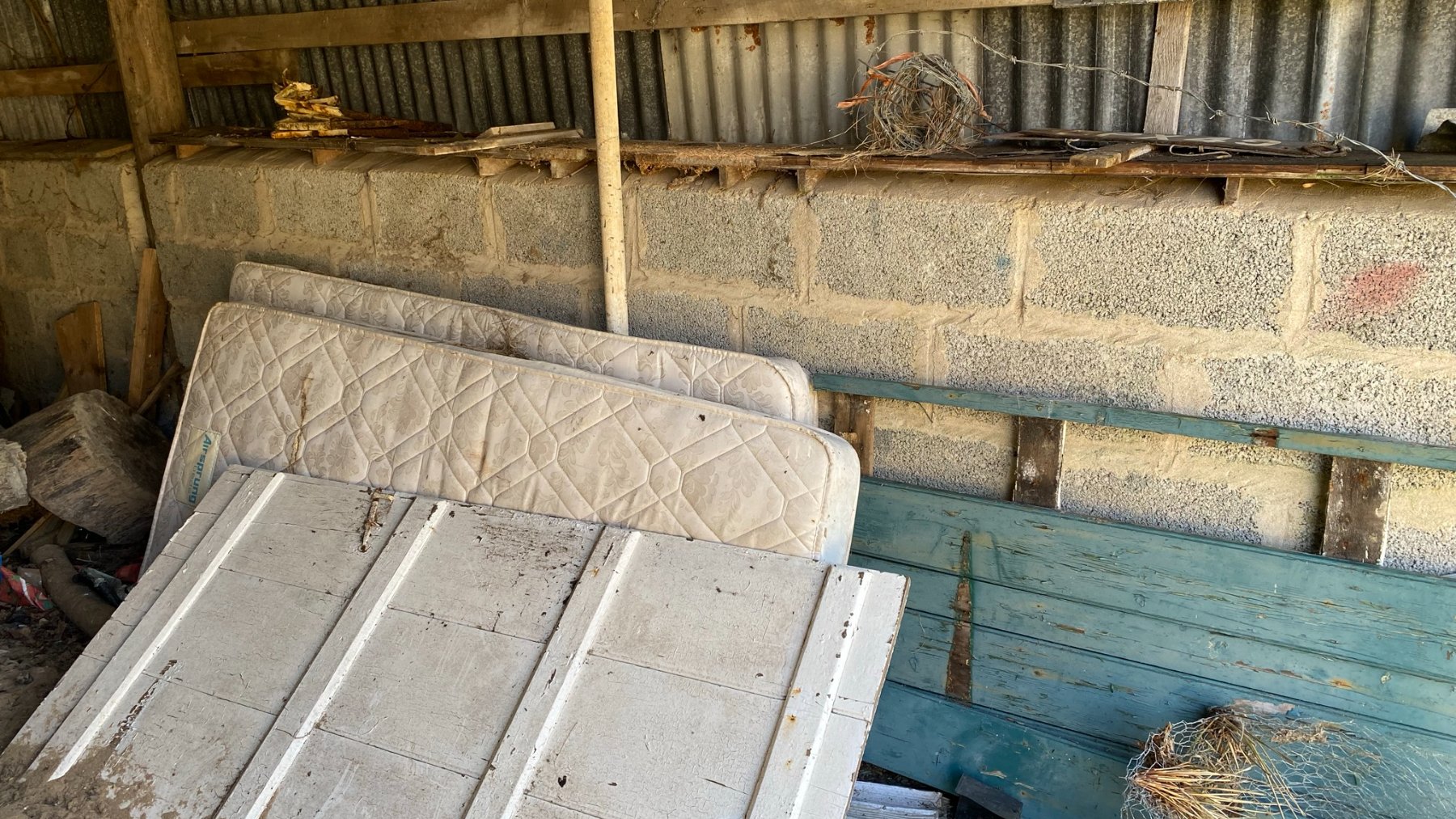 Old mattresses dumped on a street pavement next to a wall