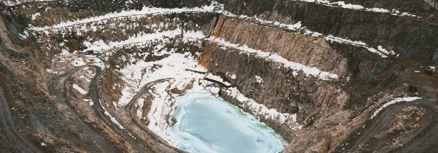 Aerial view of an open-pit mine with a turquoise pool