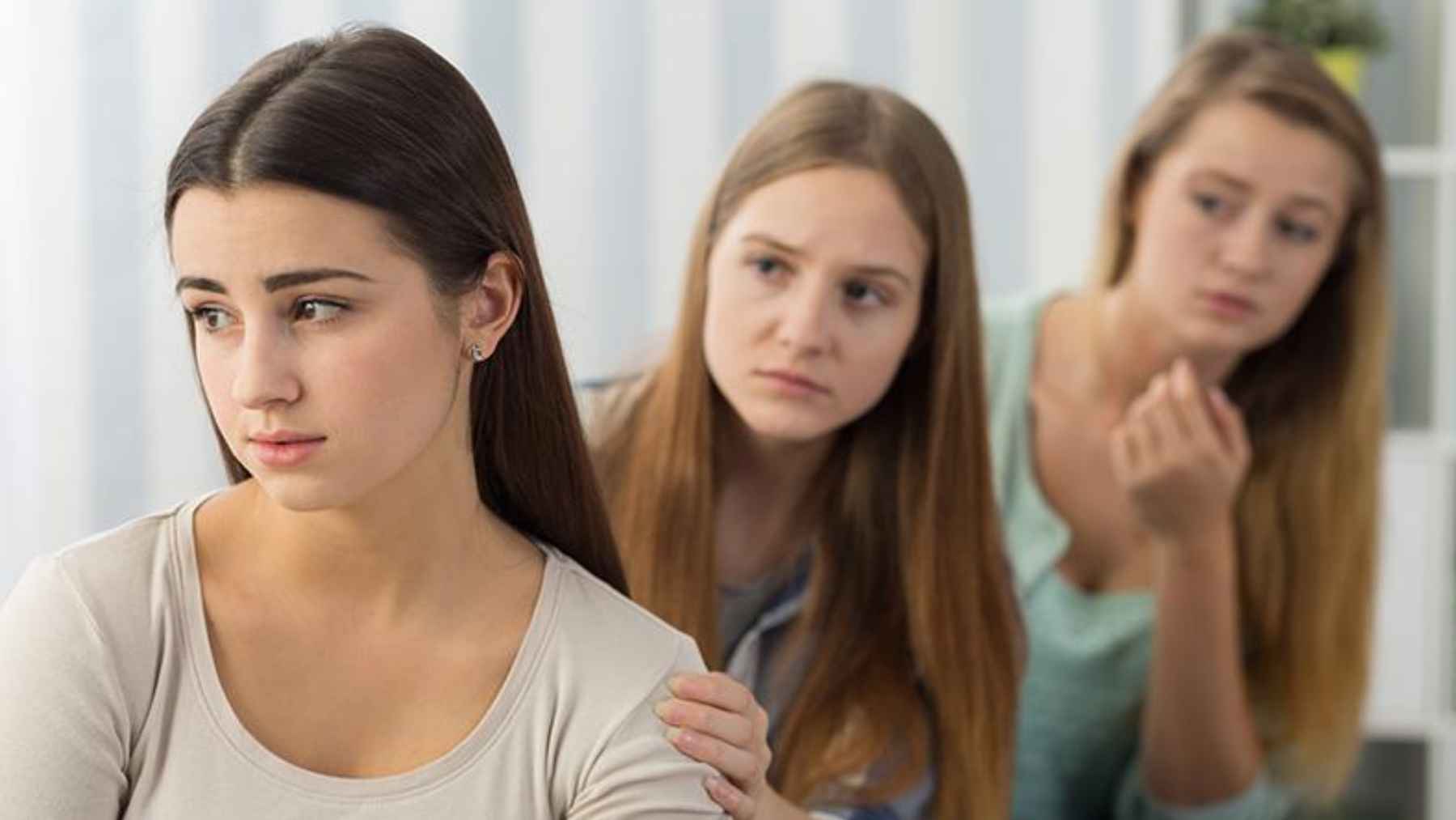 Friends offering support to a woman who appears emotionally withdrawn.