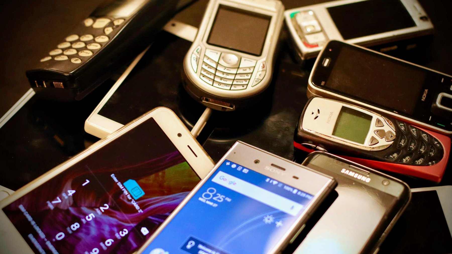 Pile of old mobile phones and smartphones, including classic keypad models