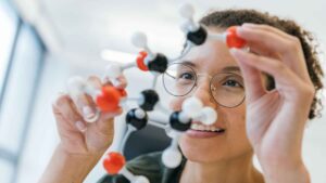 Researcher examining a ball-and-stick molecular model in a laboratory.
