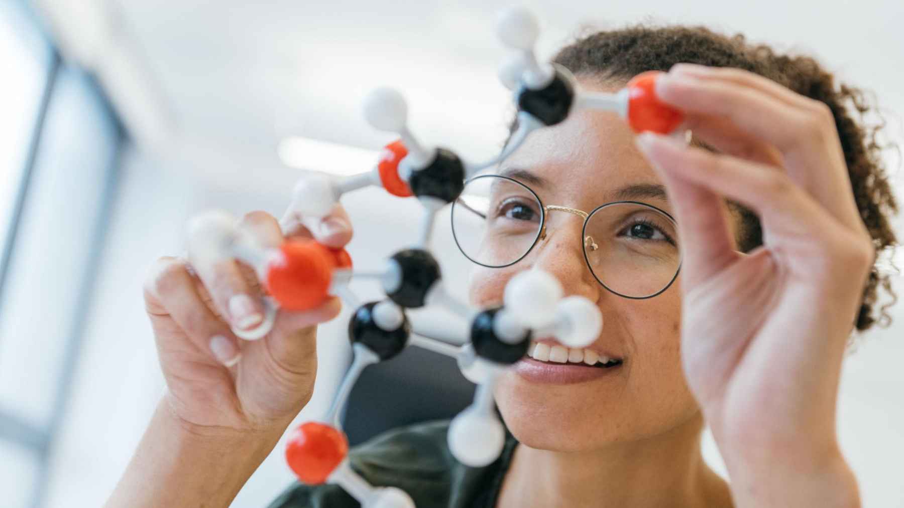 Researcher examining a ball-and-stick molecular model in a laboratory.