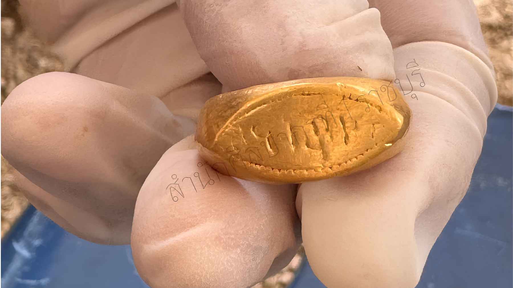 Archaeologist holding the inscribed gold ring discovered at the Don Yai Thong burial site in Thailand.