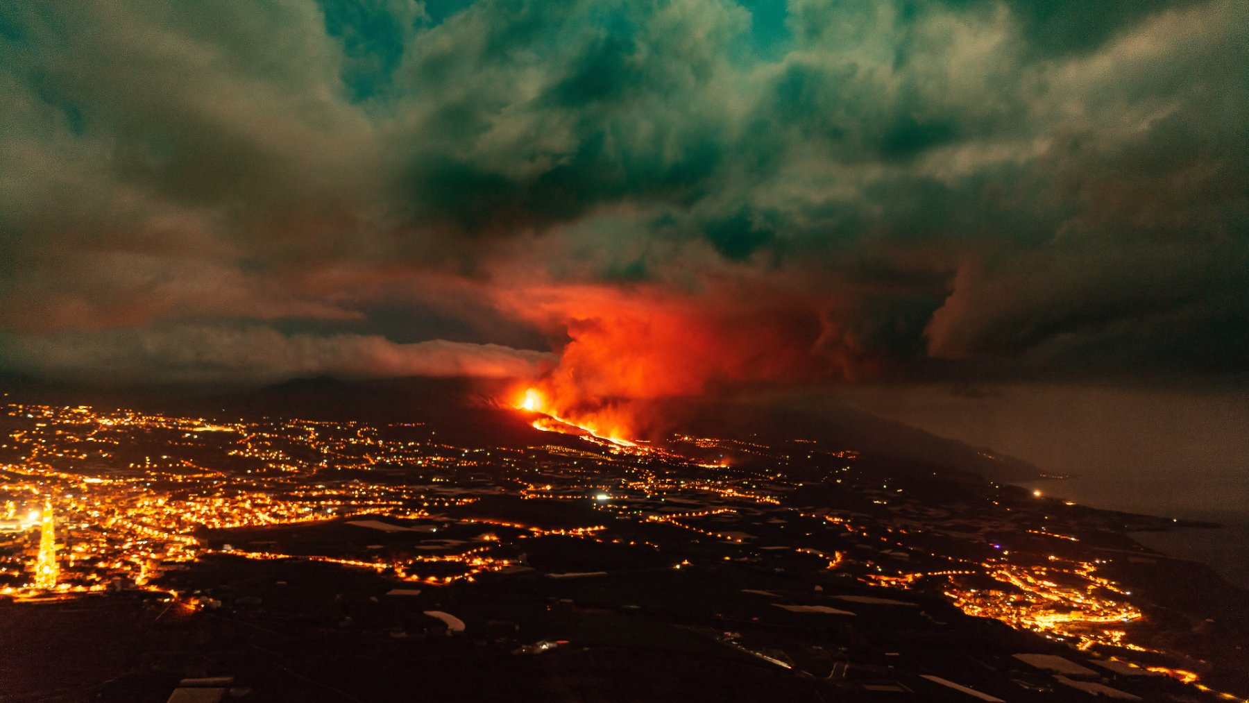 Lava and ash cloud from the La Palma volcano at night above the town lights