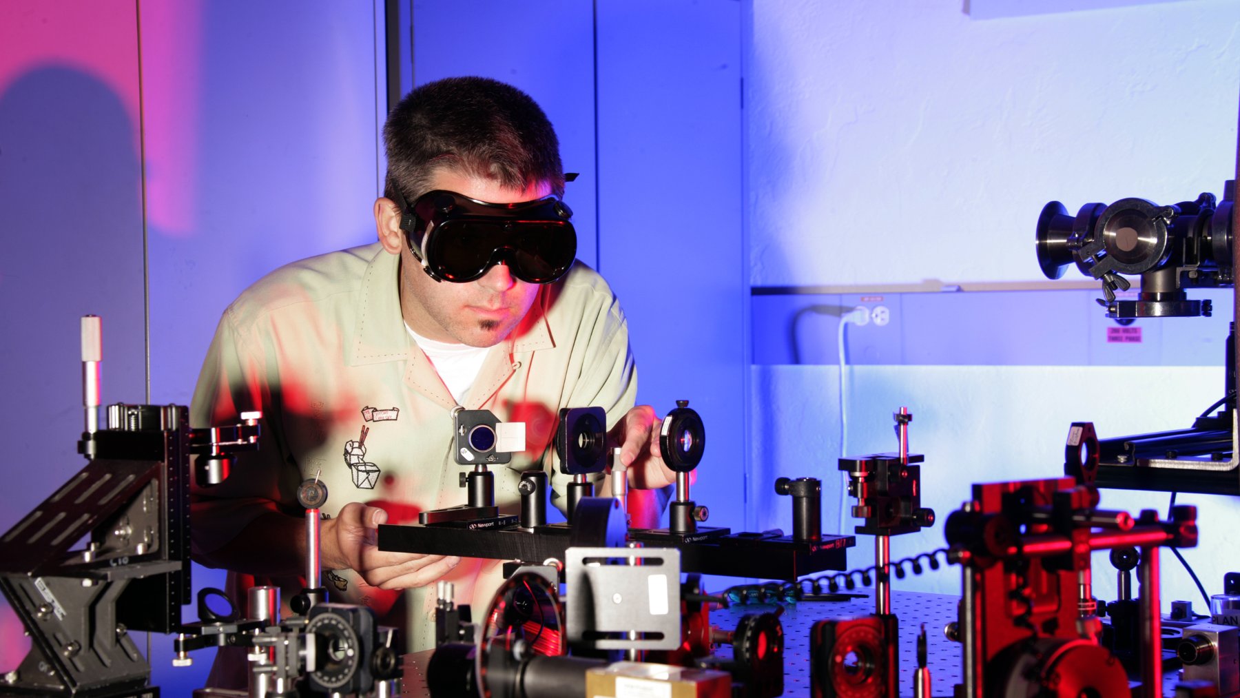 Researcher adjusting laser optics on a laboratory bench