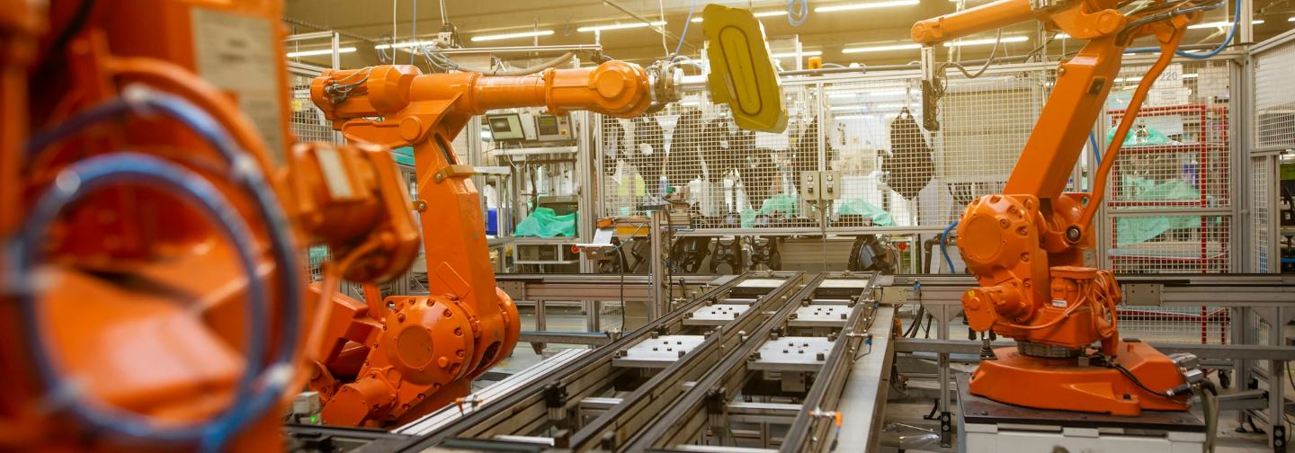 Orange industrial robots working in a factory