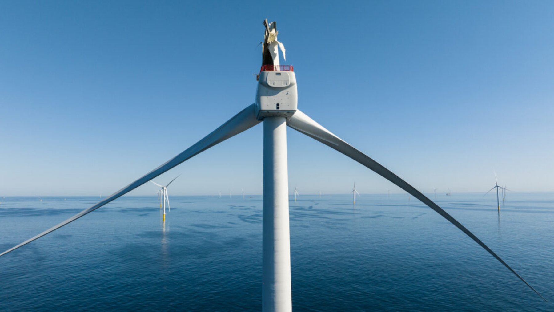 Offshore wind turbine with a damaged blade standing in calm ocean water off Nantucket
