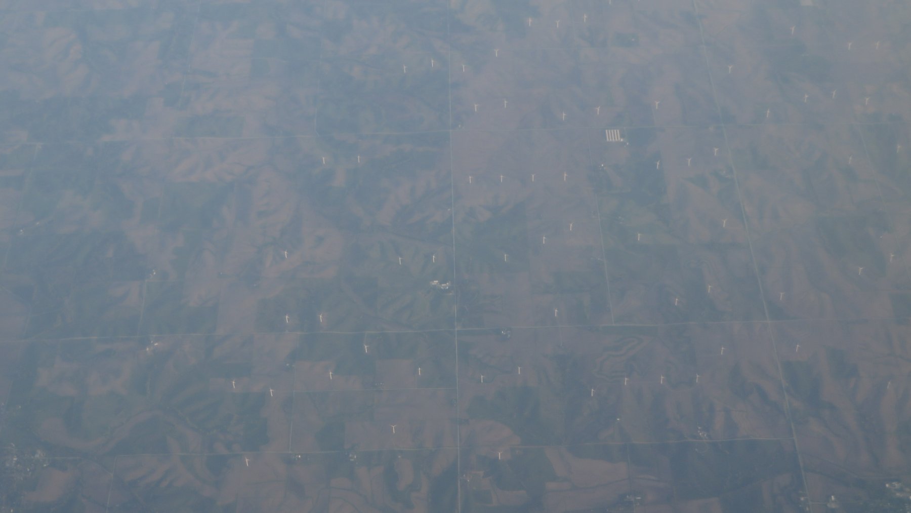 Wind turbines rising above farm fields near Massena, Iowa